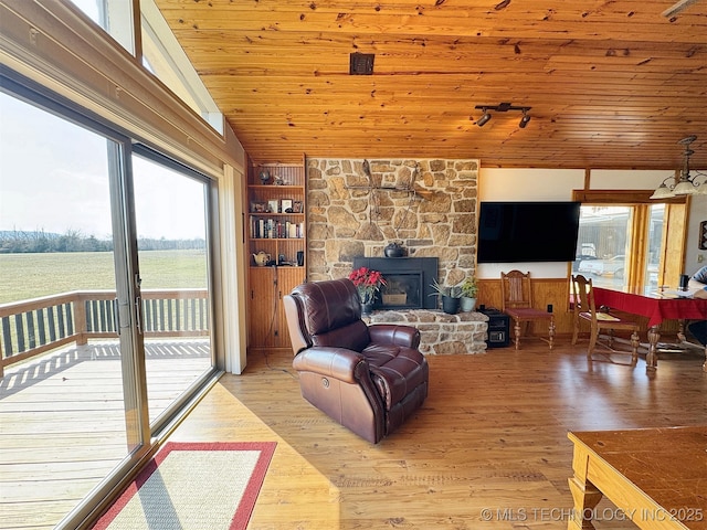 living area with lofted ceiling, wooden ceiling, rail lighting, light wood-type flooring, and a fireplace