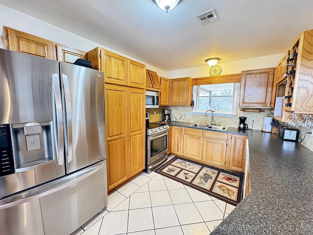 kitchen featuring stainless steel appliances, dark countertops, visible vents, decorative backsplash, and a sink