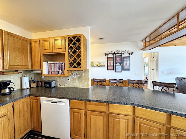 kitchen with dark countertops, visible vents, decorative backsplash, dishwasher, and a peninsula