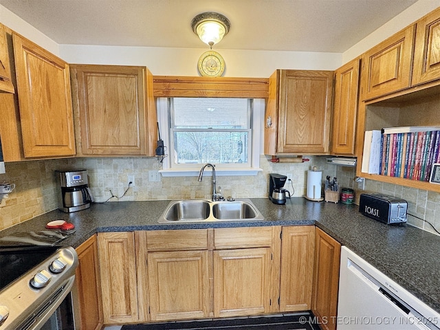 kitchen featuring dishwasher, dark countertops, a sink, and stainless steel range with electric cooktop