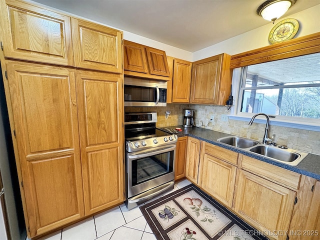 kitchen featuring tasteful backsplash, appliances with stainless steel finishes, a sink, and light tile patterned flooring