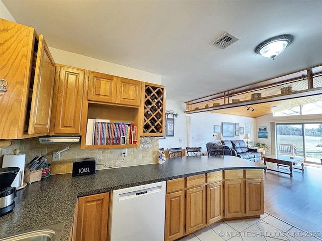 kitchen featuring tasteful backsplash, dark countertops, visible vents, vaulted ceiling, and white dishwasher