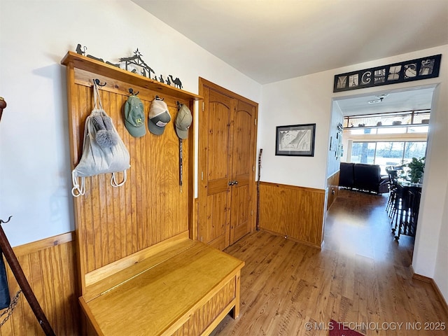 mudroom featuring a wainscoted wall, wooden walls, and light wood-style floors