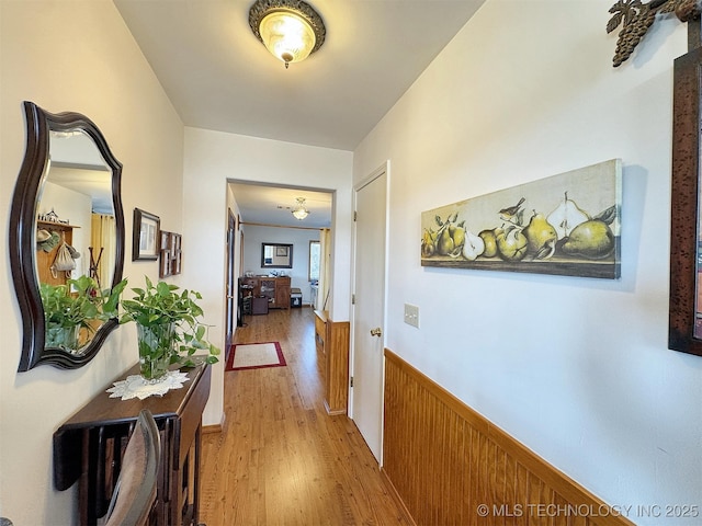 corridor with light wood-style flooring and wainscoting