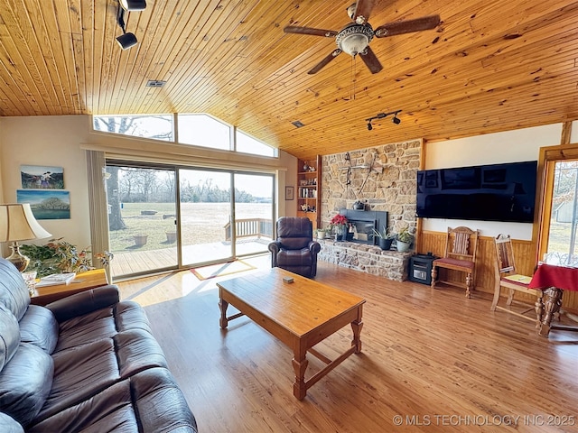 living area featuring wooden ceiling, wood finished floors, a ceiling fan, vaulted ceiling, and a wood stove