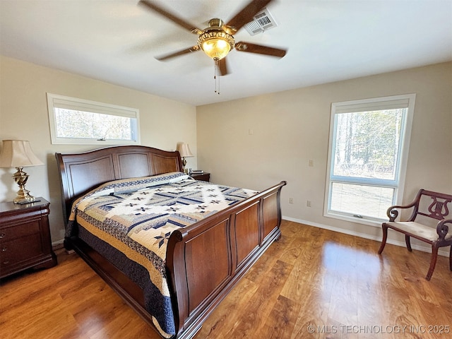 bedroom featuring visible vents, multiple windows, light wood-style flooring, and baseboards