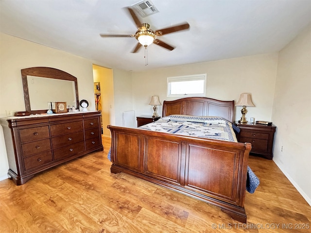 bedroom featuring baseboards, visible vents, a ceiling fan, a walk in closet, and light wood-style floors