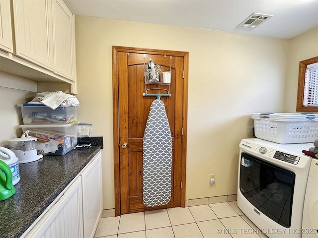 kitchen with light tile patterned floors, visible vents, baseboards, washer / clothes dryer, and dark countertops