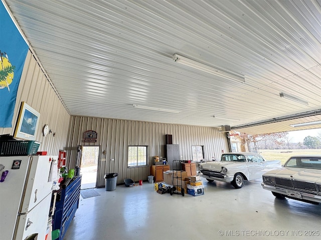 garage featuring metal wall and freestanding refrigerator