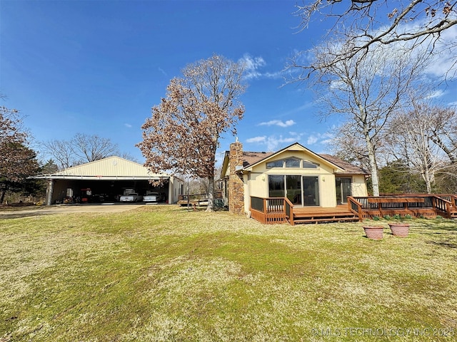 back of property with an outdoor structure, a chimney, a deck, and a yard