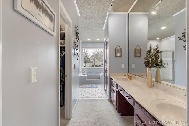 full bath with double vanity, tile patterned floors, a garden tub, a textured ceiling, and a sink