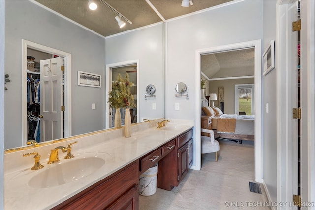 ensuite bathroom featuring double vanity, ornamental molding, a sink, and connected bathroom