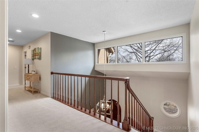 corridor with a textured ceiling, recessed lighting, carpet flooring, an upstairs landing, and baseboards