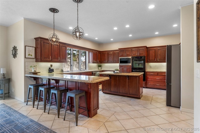 kitchen featuring dobule oven black, a peninsula, a kitchen breakfast bar, freestanding refrigerator, and stainless steel microwave