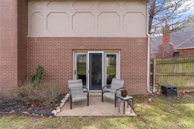 rear view of property with brick siding, fence, and a patio