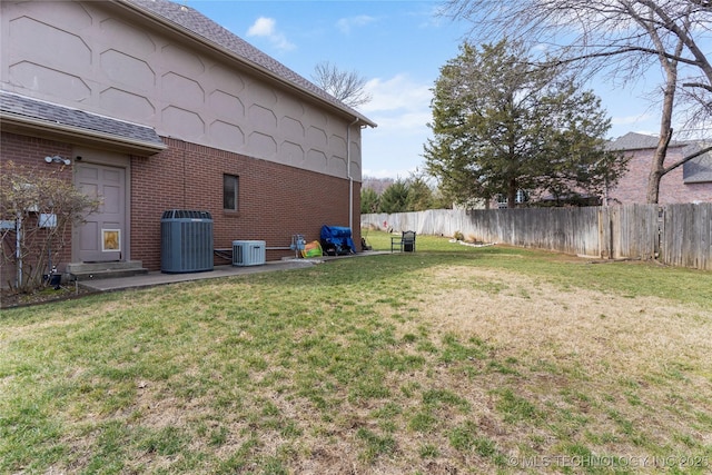 view of yard featuring central AC and fence