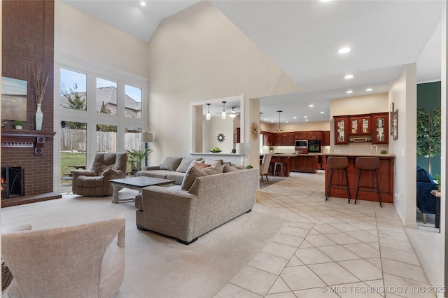 living room with recessed lighting, a brick fireplace, a towering ceiling, and light tile patterned floors