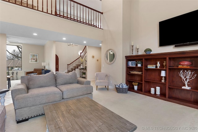 carpeted living area featuring stairs, arched walkways, a towering ceiling, and recessed lighting