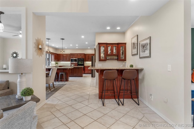 kitchen featuring black oven, a peninsula, stainless steel microwave, and a kitchen breakfast bar