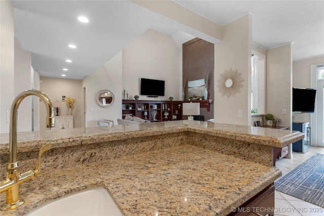 kitchen featuring open floor plan, light stone countertops, light tile patterned flooring, a sink, and recessed lighting