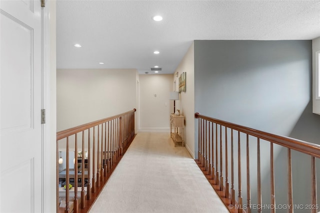 hallway with carpet, recessed lighting, a textured ceiling, an upstairs landing, and baseboards