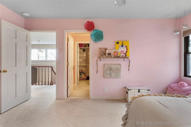 carpeted bedroom featuring a textured ceiling and baseboards