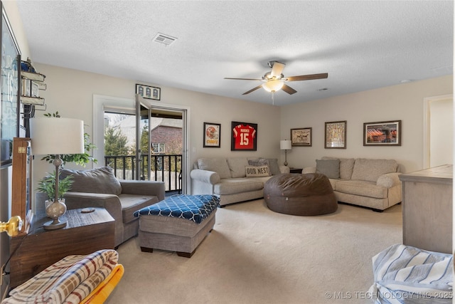 living area featuring carpet, visible vents, ceiling fan, and a textured ceiling