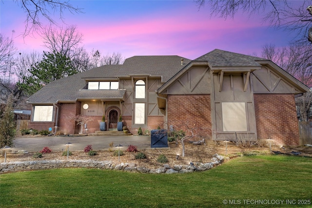 view of front of property with a front yard, brick siding, and driveway