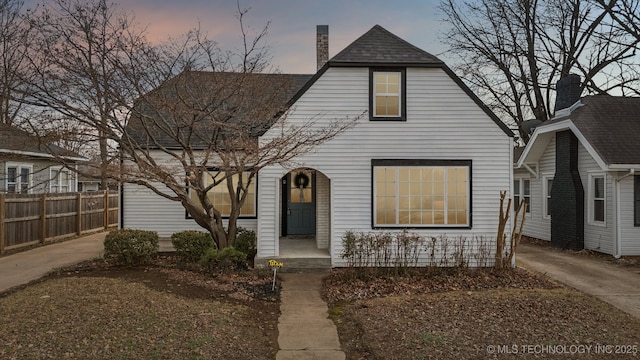 view of front of property featuring roof with shingles, a chimney, and fence