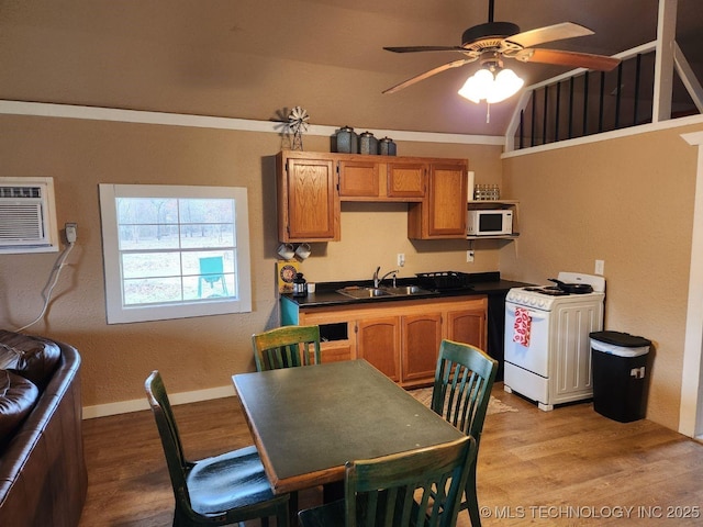 kitchen with dark countertops, white appliances, a sink, and light wood finished floors