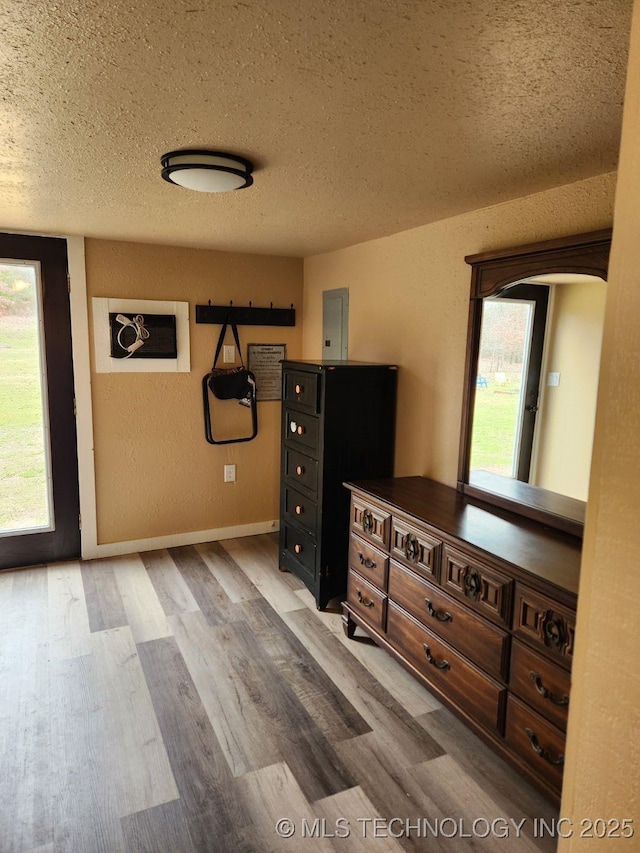 unfurnished bedroom featuring a textured ceiling, baseboards, and wood finished floors