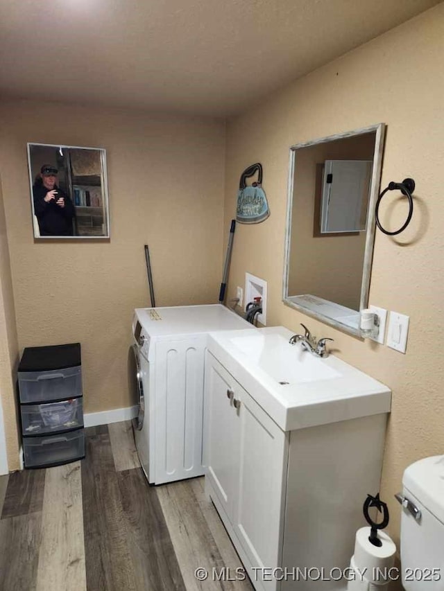 laundry area featuring laundry area, washing machine and dryer, a sink, and wood finished floors