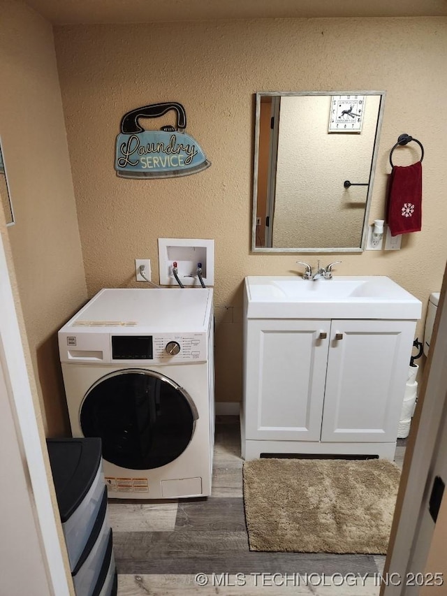 laundry room with washer / dryer, wood finished floors, cabinet space, and a textured wall