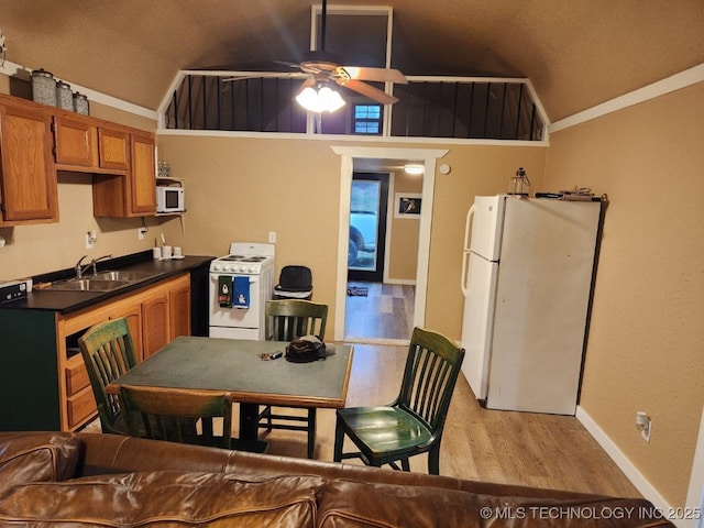 kitchen featuring white appliances, a sink, vaulted ceiling, brown cabinets, and light wood finished floors