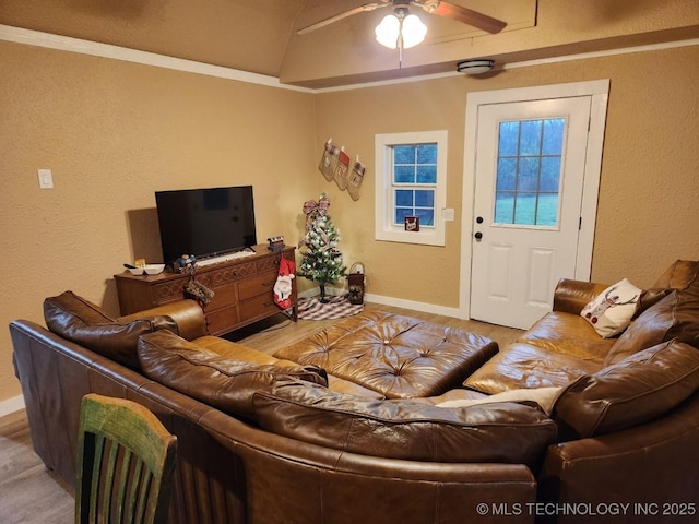 living room featuring a textured wall, vaulted ceiling, ceiling fan, wood finished floors, and baseboards