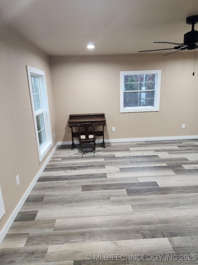 unfurnished room with baseboards, a wealth of natural light, and wood finished floors