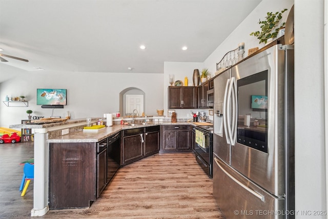 kitchen featuring light wood finished floors, black appliances, dark brown cabinets, and a sink