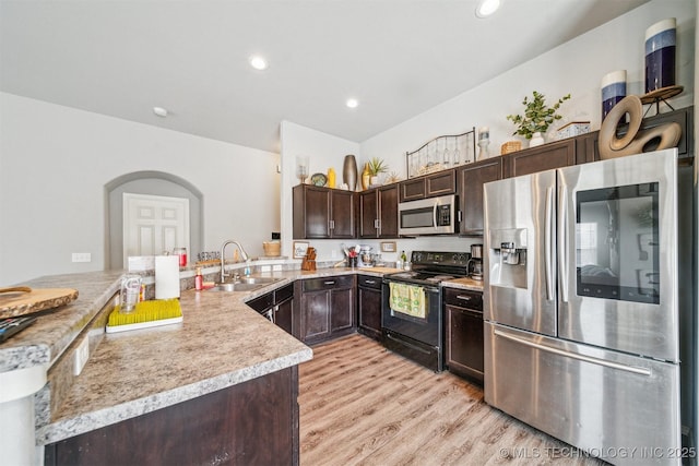 kitchen featuring light countertops, appliances with stainless steel finishes, a sink, dark brown cabinets, and a peninsula