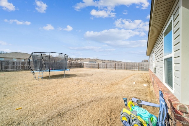 view of yard featuring a trampoline and a fenced backyard