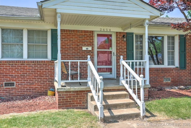 entrance to property featuring a shingled roof, crawl space, and brick siding