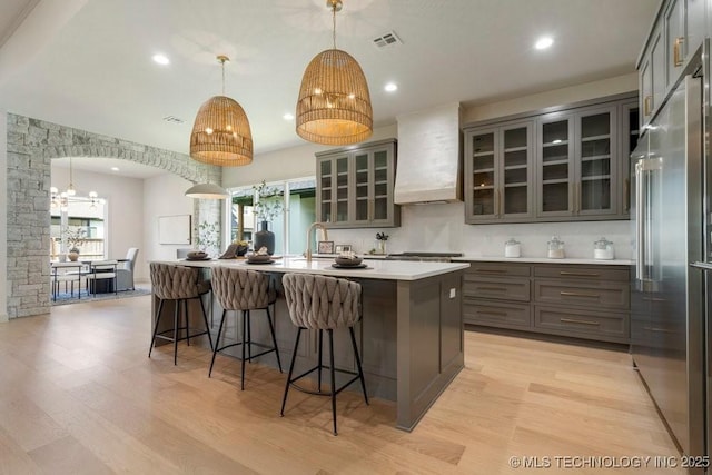 12030 S Vandalia Ave, Tulsa, OK 74137 - kitchen featuring high quality fridge, premium range hood, light wood-style floors, a kitchen bar, and a center island with sink