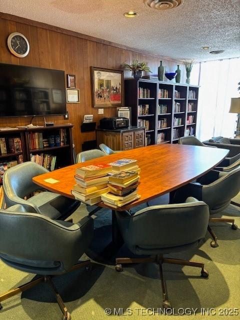 office featuring wooden walls, carpet, and a textured ceiling