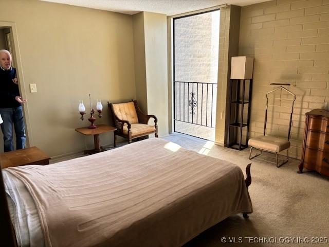 bedroom with a textured ceiling, carpet floors, access to outside, and a wall of windows