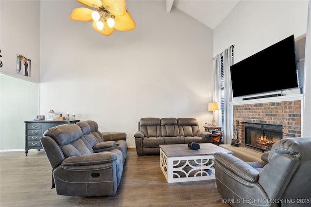 living area with high vaulted ceiling, a fireplace, wood finished floors, a ceiling fan, and baseboards