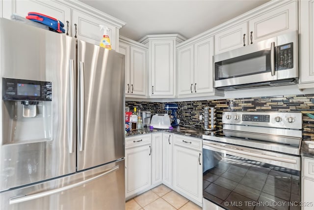 kitchen with light tile patterned flooring, stainless steel appliances, white cabinets, backsplash, and dark stone counters