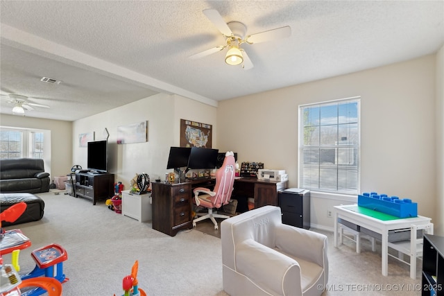 home office with a textured ceiling, carpet flooring, visible vents, and a ceiling fan