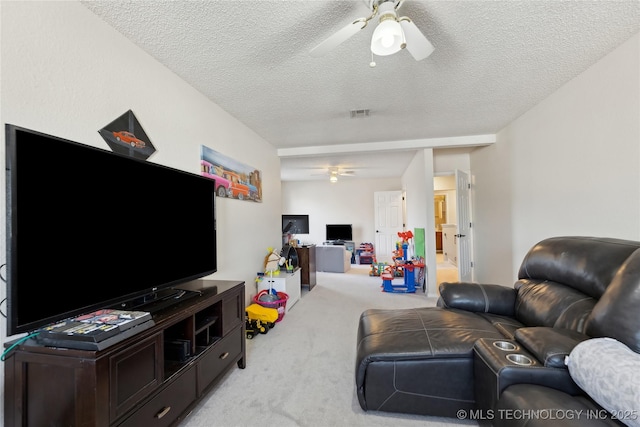 living room with a textured ceiling, visible vents, a ceiling fan, and light colored carpet