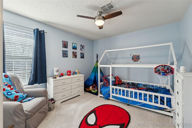 carpeted bedroom featuring a ceiling fan, visible vents, and a textured ceiling