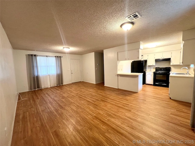 kitchen featuring open floor plan, a sink, light wood-style flooring, and black appliances