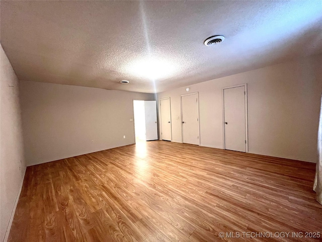 interior space featuring a textured ceiling, light wood-type flooring, and visible vents